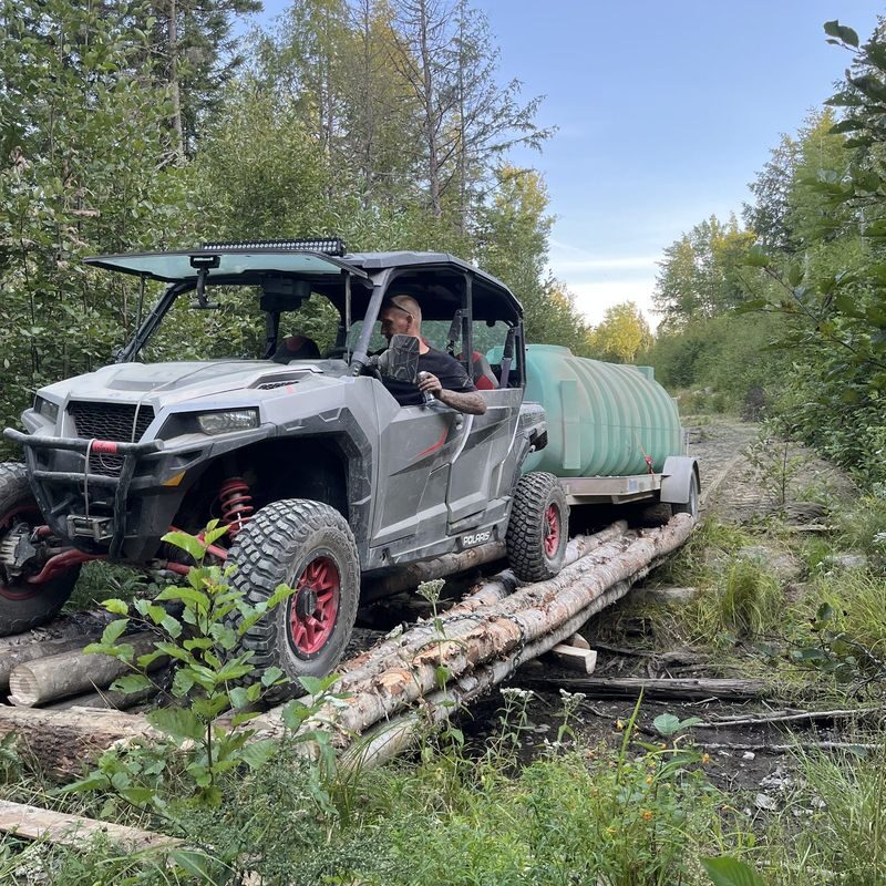 Polaris UTV hauling tank over log bridge